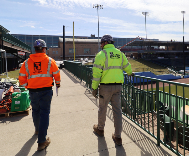Two construction workers walk a project site reviewing work completed