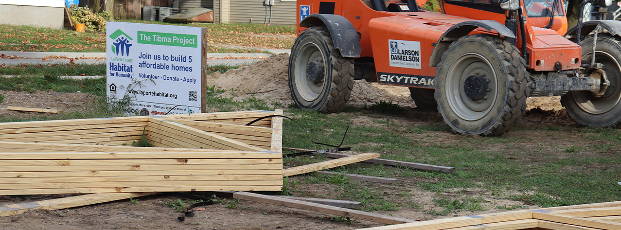 A Larson-Danielson Lift sits behind roof trusses and the Tibma Project site sign
