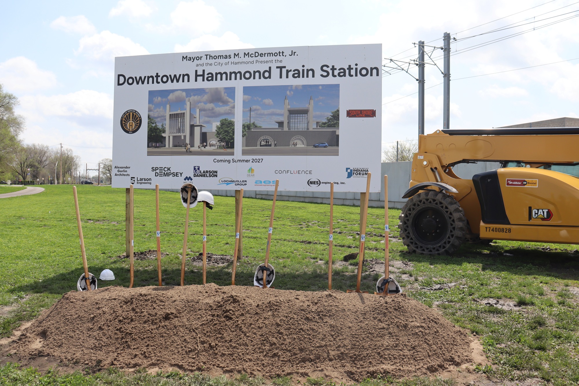 A sign displays renderings and logos of the project team for the new Downtown Hammond Train Station