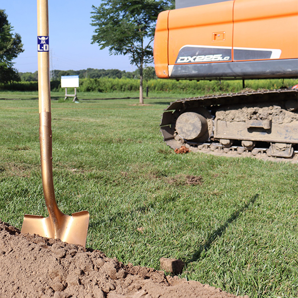 A ceremonial shovel in a pile of dirt on a grassy site